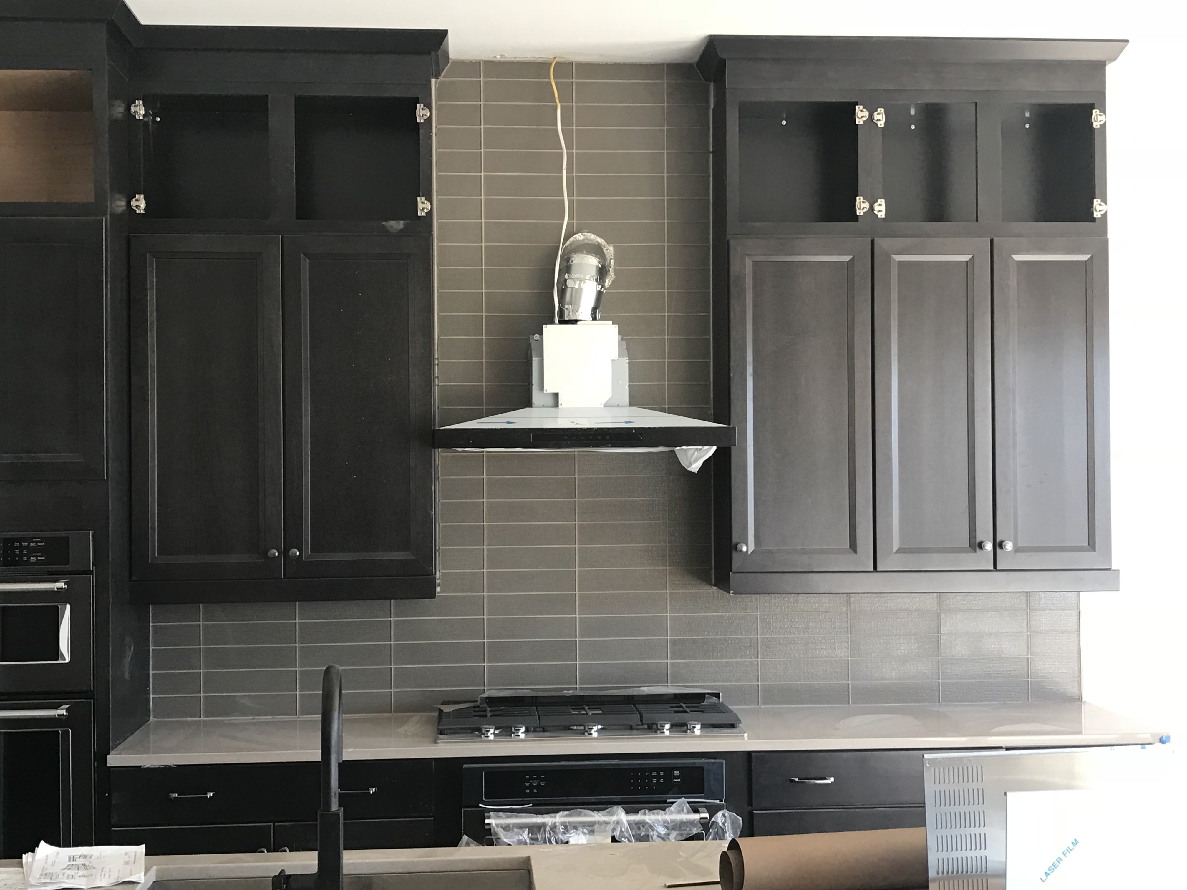 Dark charcoal shaker cabinets and gray backsplash during professional kitchen installation