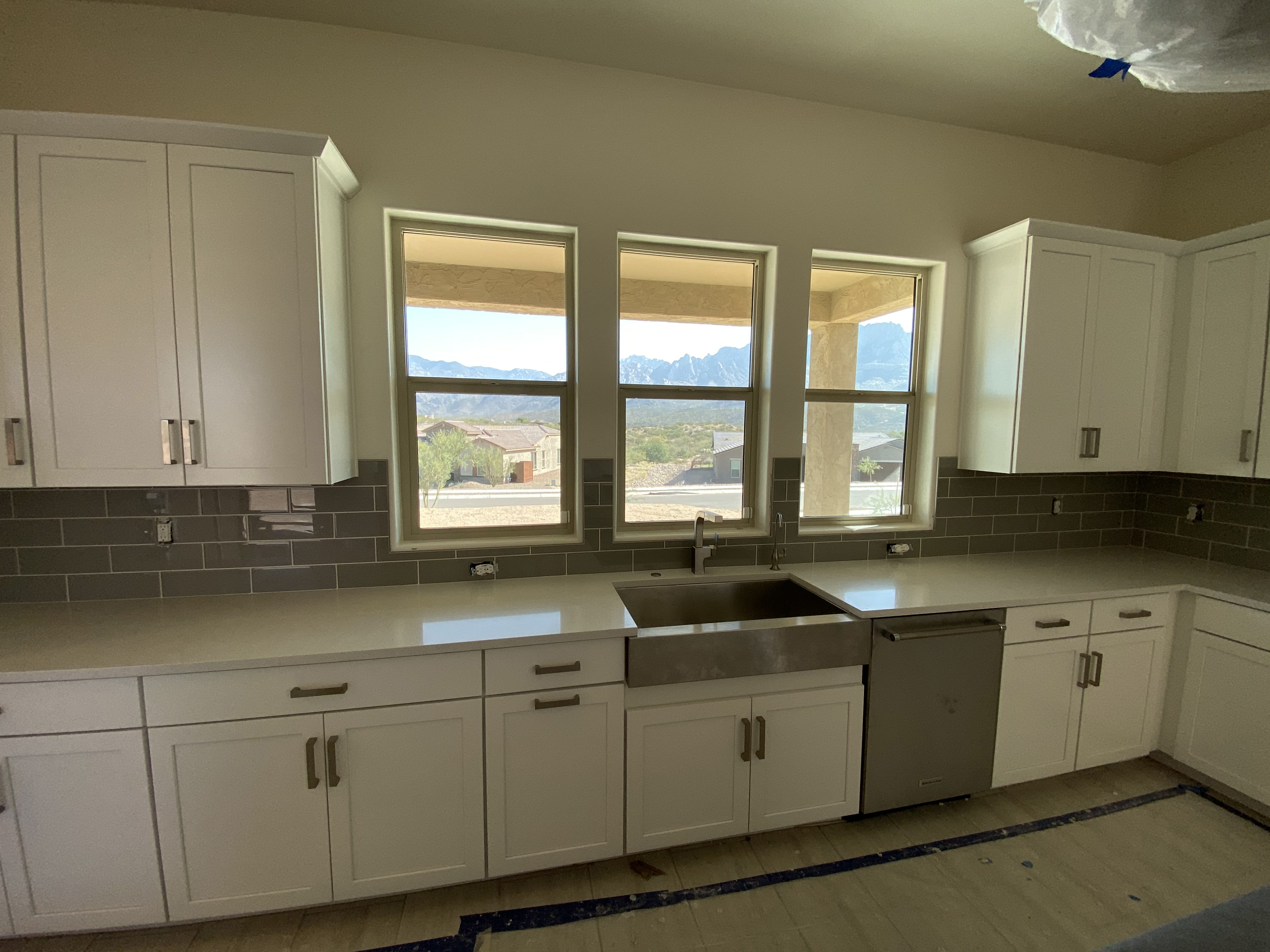 Light gray kitchen cabinets with glass uppers, white countertops, and mosaic tile backsplash